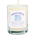 A white votive candle labeled 'Astral Journey' with a candle burning on top, placed in a clear glass holder with a label that includes an inspirational message.