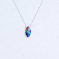 Bijou Seed Necklace by Mosaico Jewels featuring a vibrant, colorful seed pendant adorned with crystals, set against a light background.
