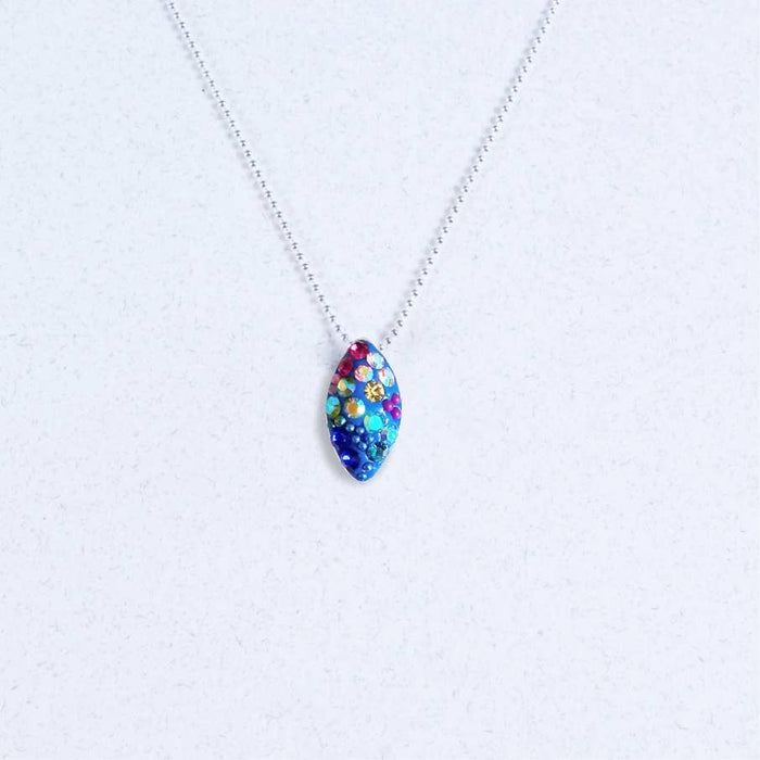 Bijou Seed Necklace by Mosaico Jewels featuring a vibrant, colorful seed pendant adorned with crystals, set against a light background.