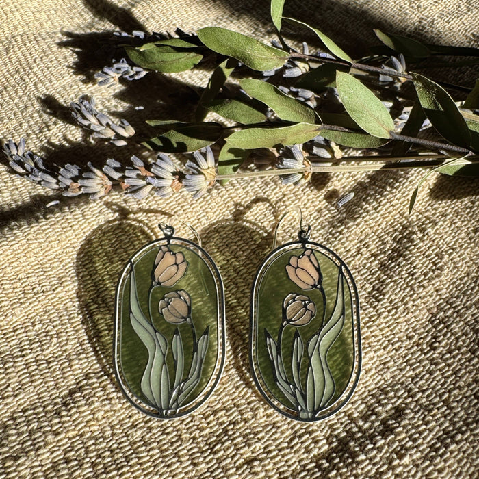 Camellias Stained Glass Resin Earrings by Wild Lupine Folkcraft, showcasing a stainless steel botanical design infused with soft-colored resin, beautifully catching the light against a natural background.