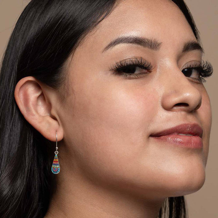 Close-up of a model wearing Fairy Teardrop Earrings by Mosaico Jewels, showcasing their delicate design and vibrant colors against a neutral backdrop.