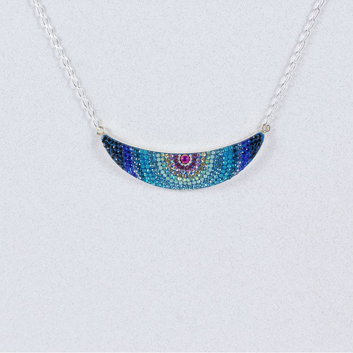 Elegant Luna Crystal Necklace by Mosaico Jewels featuring a beautiful gradient of blue beads in a crescent moon shape, presented on a light gray background.