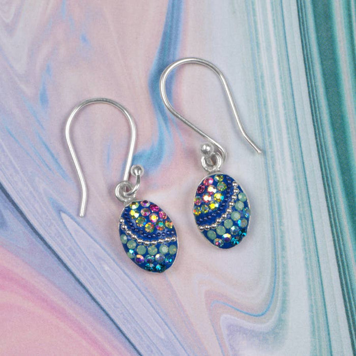 Colorful Petite Oval Earring by Mosaico Jewels displayed on a pastel marble background, showcasing its shimmering design with colorful accents.