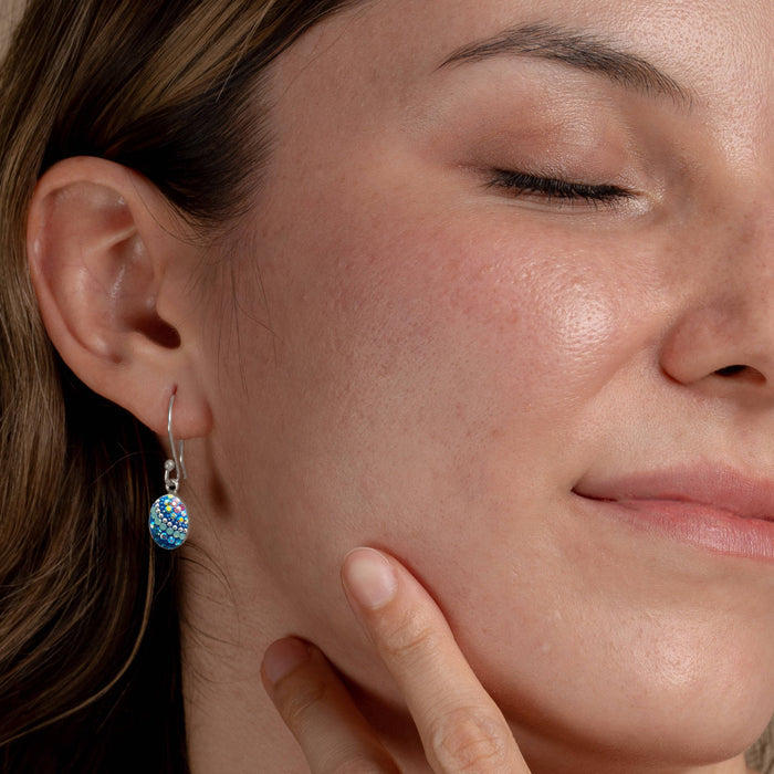 Model wearing the Petite Oval Earring by Mosaico Jewels, highlighting the earring's elegance and style against a soft-focused portrait.