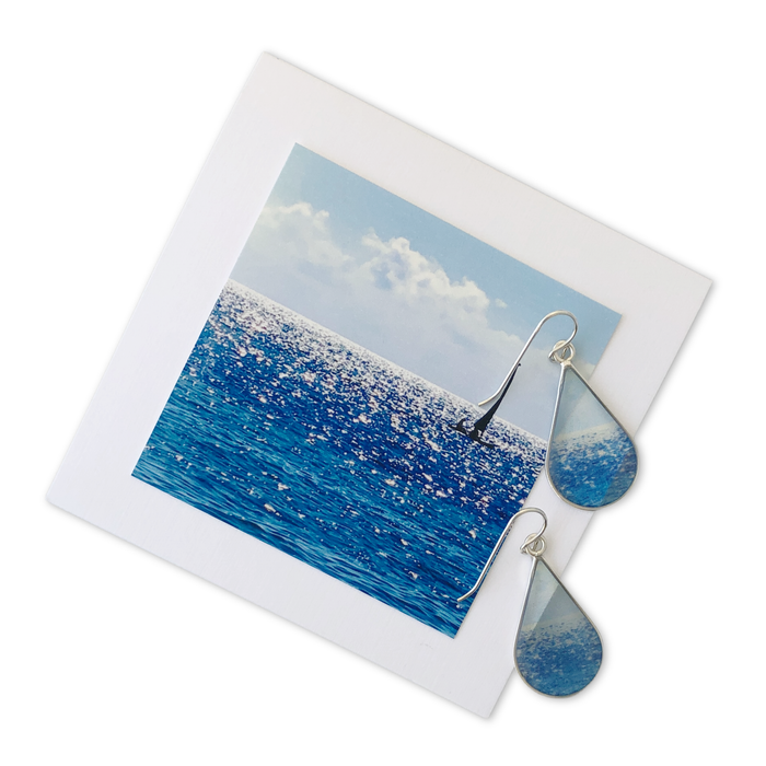 Shining Sea Small Teardrop Earrings by Foterra Jewelry displayed with a vibrant ocean-inspired photo background, showcasing their elegant and lightweight design.