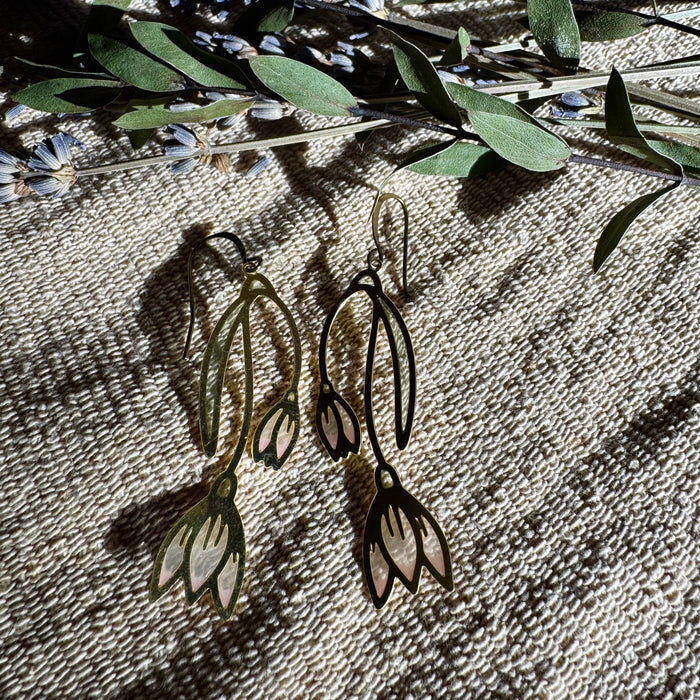Snowdrop Stained Glass Resin Earrings by Wild Lupine Folkcraft, showcasing a unique and colorful handmade design against a natural backdrop of greenery.